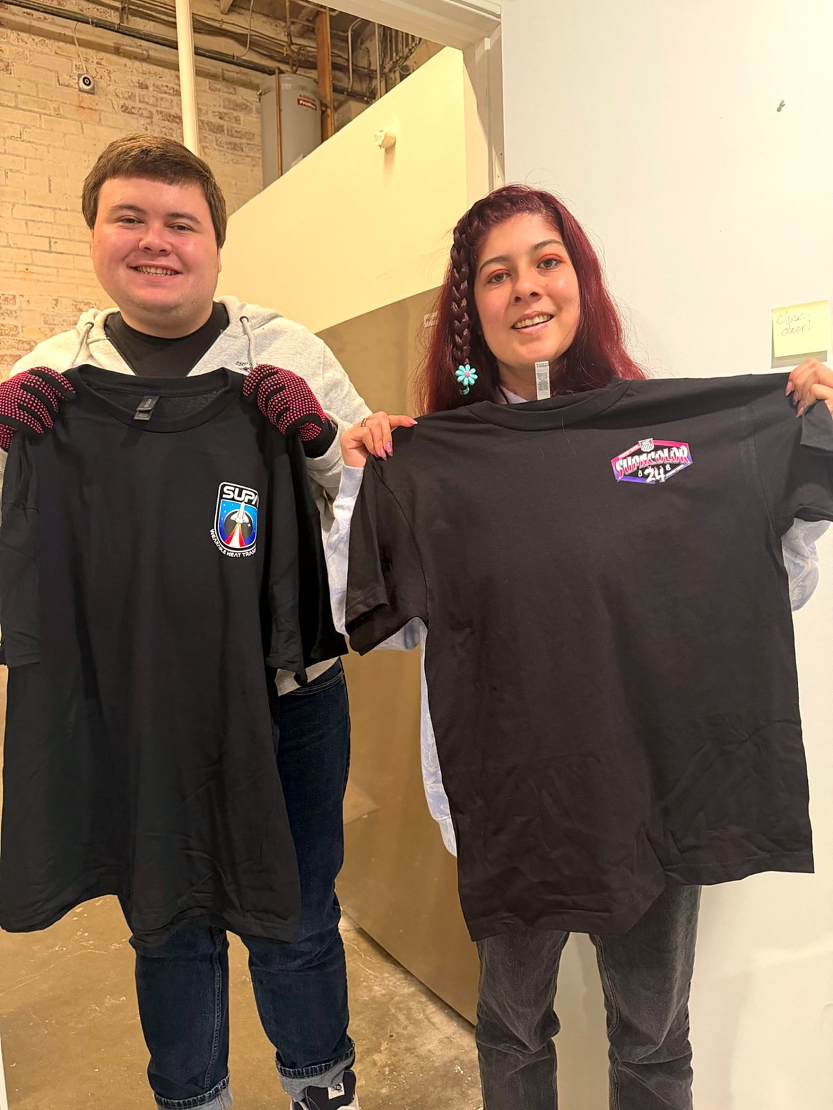 A participant and a team member showing two printed shirts from a customer order